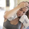 Young woman sweating and resting in a gym after an intense workout session.