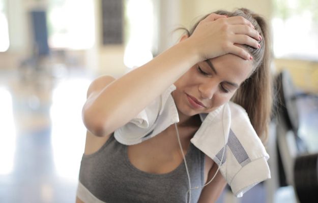 Young woman sweating and resting in a gym after an intense workout session.
