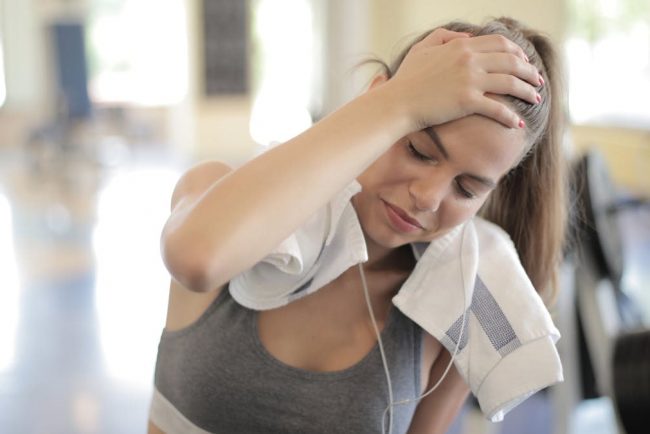 Young woman sweating and resting in a gym after an intense workout session.