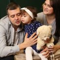 a man, woman and child sitting in front of a christmas tree