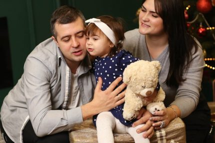 a man, woman and child sitting in front of a christmas tree
