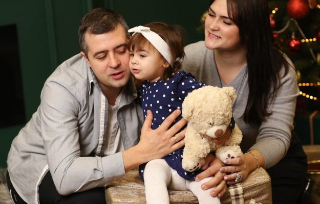a man, woman and child sitting in front of a christmas tree