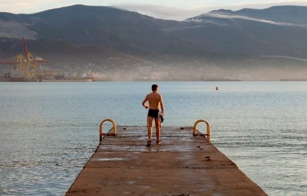 a man standing on a dock looking out at the water
