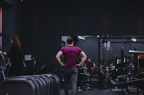Man in a gym with fitness equipment, highlighting a healthy lifestyle.